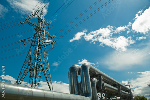 pipeline and power line support, in the photo pipeline and power line tower close-up against the background of blue sky and clouds