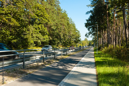 a highway and a sidewalk, in the photo a road and a sidewalk in a forest belt