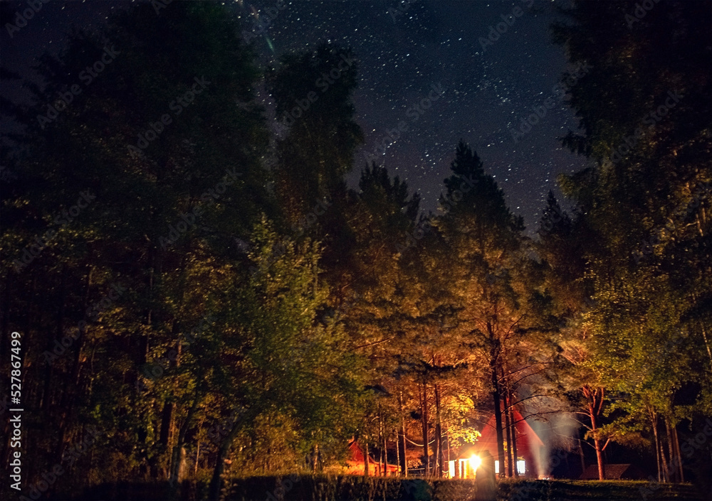 Stars on dark sky over country house. Cozy cabin in the forest under a very starry sky. A fantastic combination of the eternal and the transitory. august.