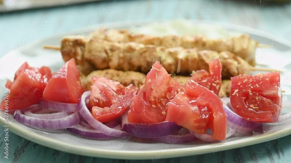The cook sprinkles the greek chicken souvlaki with oregano.
The cook sprinkles the greek chicken souvlaki with oregano.