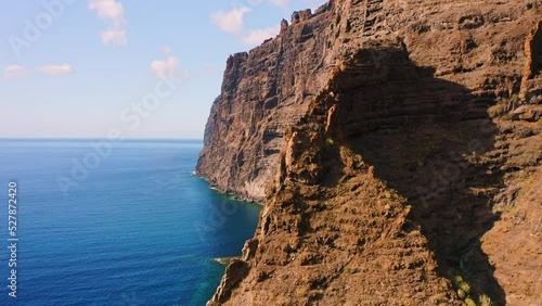 Aerial view reveal of mountains on the blue ocean in Tenerife, Canary islands, Spain. Clear morning sky. Los Gigantes cliffs. Huge barren rocks. Tranquil deep azure Atlantic waters. photo