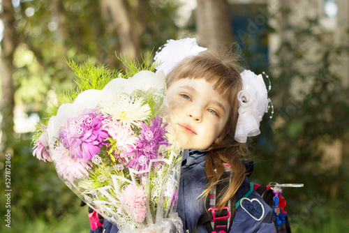 Cute girl with a white bow with flowers, first time in first grade photo