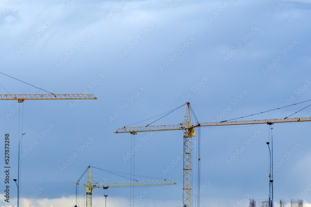 Construction cranes on a blue sky background. Space for copying text