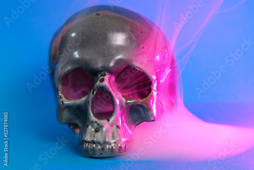 Human skull in pink and blue smoke on a blue background. Halloween concept