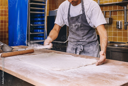 Crop cook sprinkling flour on dough