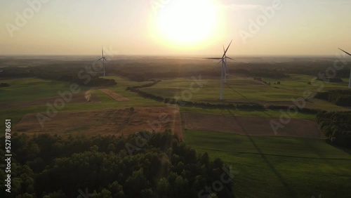 Green energy, electricity concept. Aerial cinematic drone panoramic shot of windmills and electricity wind turbines farm. Summer sunset sunny golden hours evening time. Panoramic European nature view