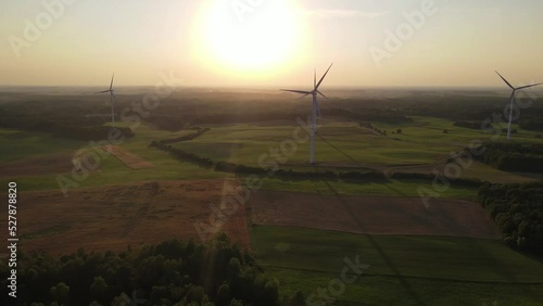Green energy, electricity concept. Aerial cinematic drone panoramic shot of windmills and electricity wind turbines farm. Summer sunset sunny golden hours evening time. Panoramic European nature view