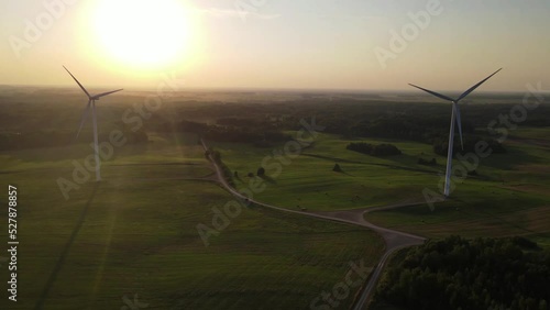 Green energy, electricity concept. Aerial cinematic drone panoramic shot of windmills and electricity wind turbines farm. Summer sunset sunny golden hours evening time. Panoramic European nature view