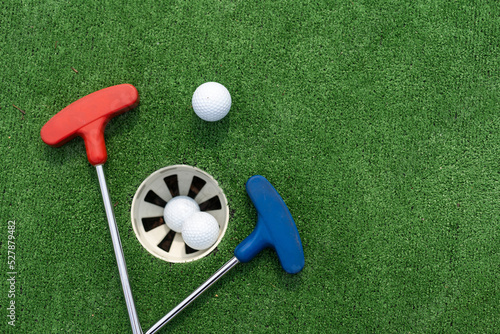 Valokuva Assorted miniature golf putters and balls askew on synthetic grass