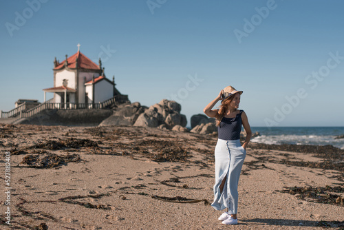 Glad traveler on sandy ocean shore against old chantry