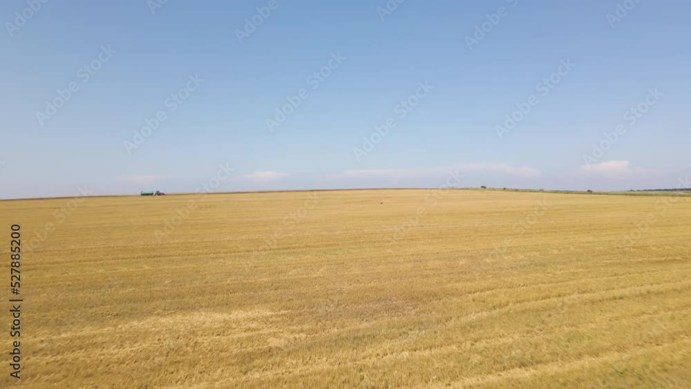 Tractor with water tank trailer driving on dirt road between agricultural fields during harvest season Tractor with water tank trailer driving on dirt road between agricultural fields during harvest season