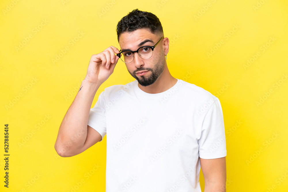 Fototapeta premium Young Arab handsome man isolated on yellow background With glasses and frustrated expression