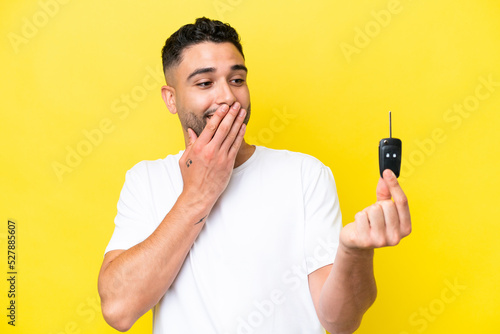Young Arab man holding car keys isolated on yellow background with surprise and shocked facial expression