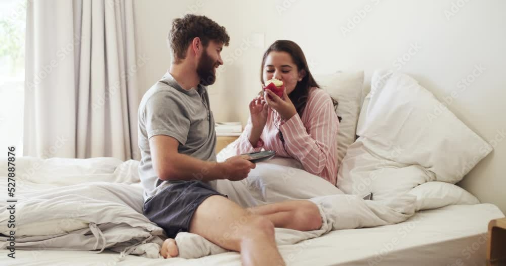 Couple eating a cupcake for birthday breakfast in bed to celebrate with cake in bedroom of vacation home and giving gift for love in morning. Happy man and woman celebrating anniversary with food Couple eating a cupcake for birthday breakfast in bed to celebrate with cake in bedroom of vacation home and giving gift for love in morning. Happy man and woman celebrating anniversary with food