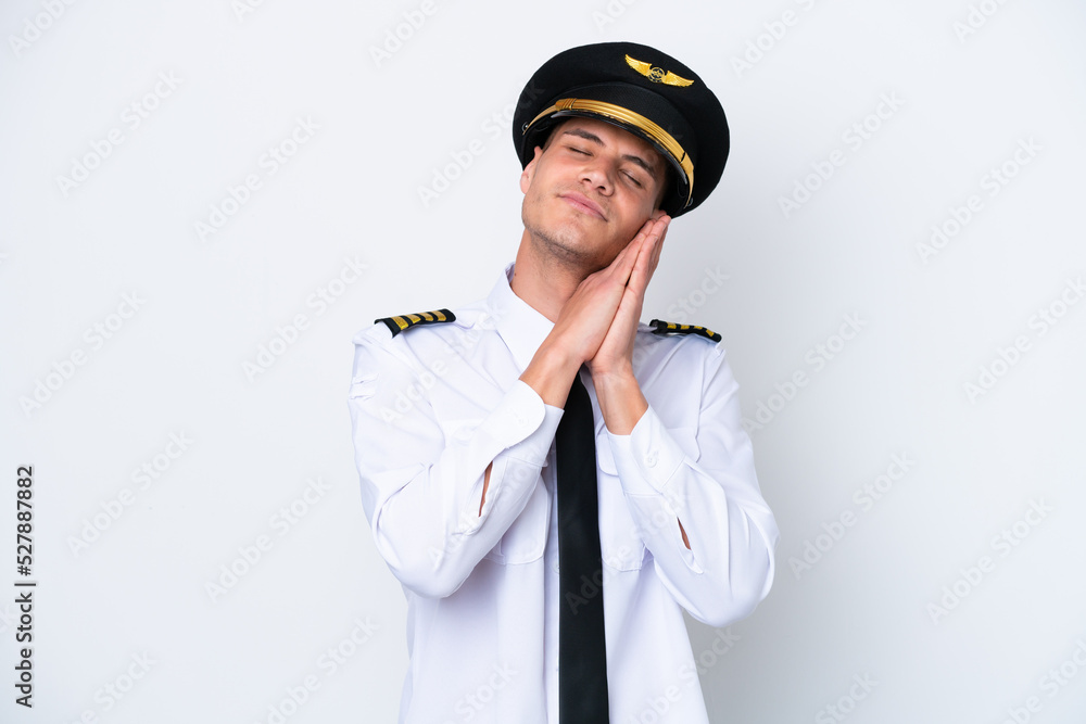 Airplane caucasian pilot isolated on white background making sleep gesture in dorable expression Airplane caucasian pilot isolated on white background making sleep gesture in dorable expression