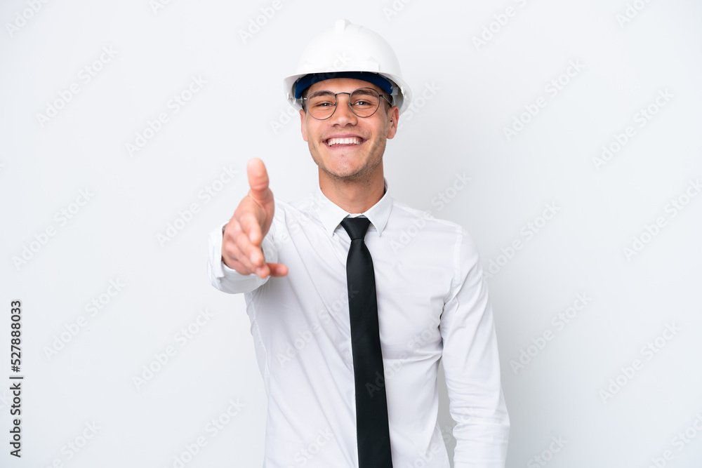 Young architect caucasian man with helmet and holding blueprints isolated on white background shaking hands for closing a good deal