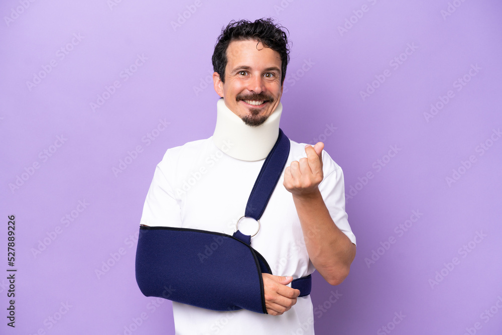 Young caucasian man wearing a sling and neck brace isolated on purple background making money gesture Young caucasian man wearing a sling and neck brace isolated on purple background making money gesture