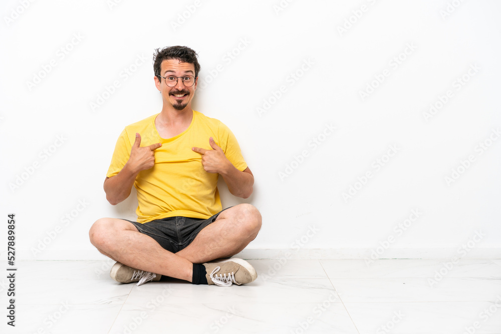 Fototapeta premium Young caucasian man sitting on the floor isolated on white background with surprise facial expression