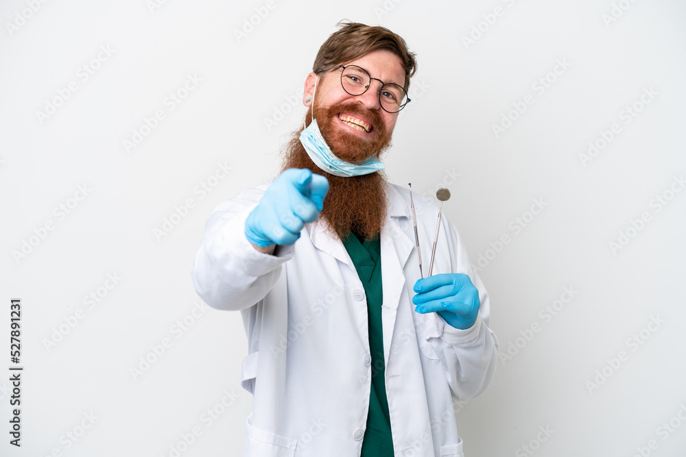 Dentist reddish man holding tools isolated on white background pointing front with happy expression Dentist reddish man holding tools isolated on white background pointing front with happy expression