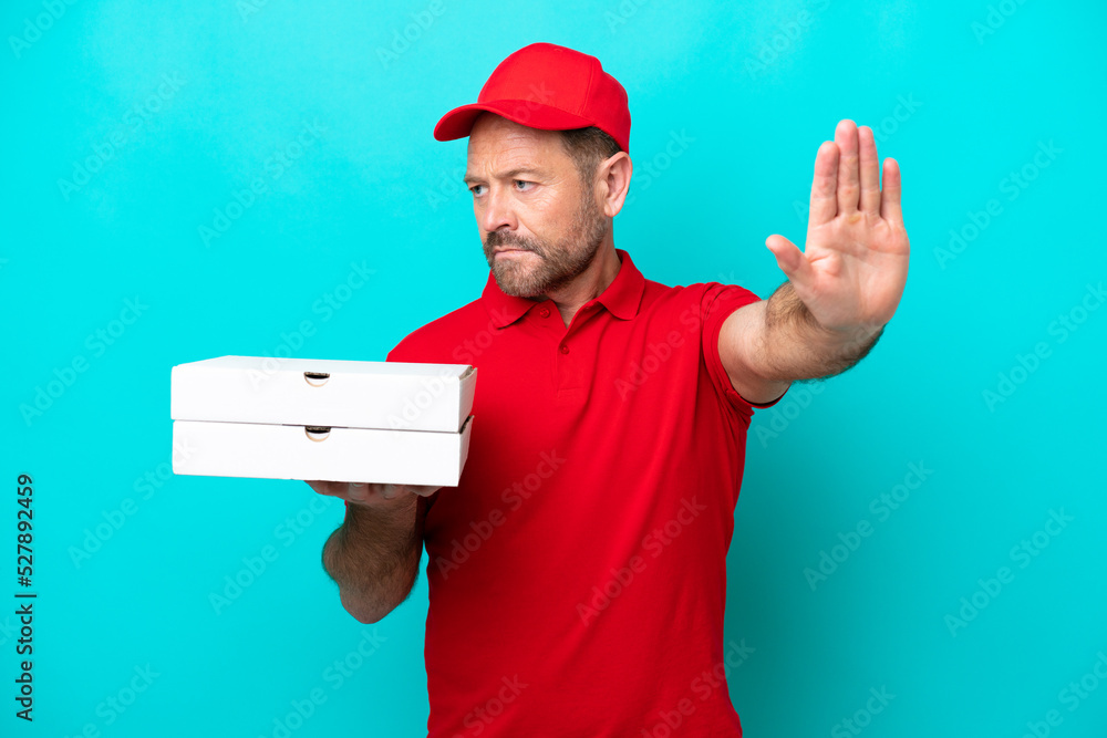 Pizza delivery man with work uniform picking up pizza boxes isolated on blue background making stop gesture and disappointed Pizza delivery man with work uniform picking up pizza boxes isolated on blue background making stop gesture and disappointed