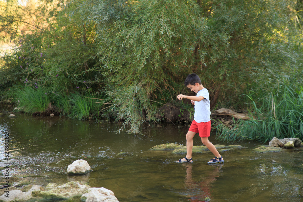 child having fun getting his feet wet in the river in summertime child having fun getting his feet wet in the river in summertime