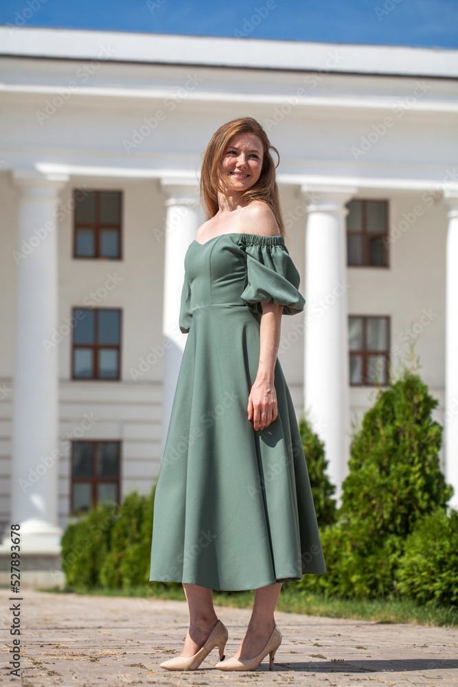 Portrait of a young beautiful red hair in green long dress