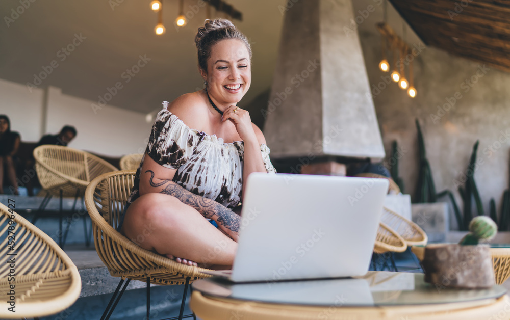 Carefree Swedish woman sitting front open laptop computer while working remote on freelance. Smiling tattooed female digital nomad work on netbook. Studying with webinar. Online Shopping on website Carefree Swedish woman sitting front open laptop computer while working remote on freelance. Smiling tattooed female digital nomad work on netbook. Studying with webinar. Online Shopping on website