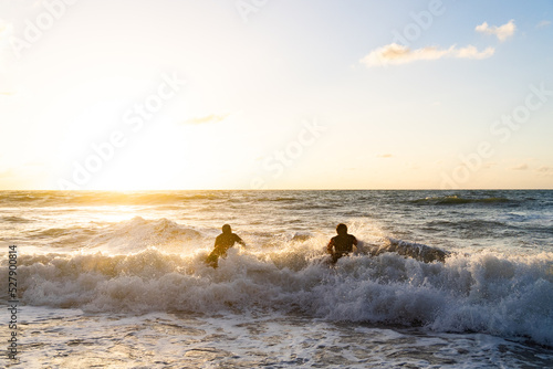 Friends going surf in the sunrise, Maceío, Brazil 