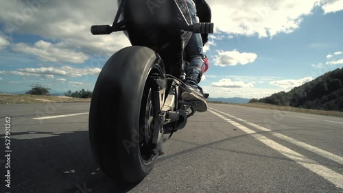 Close up of a stunt biker on a motor bike on road with smoke of the tire
