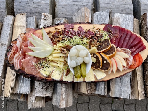 Typical Grisons snack plate containing dried meat and cheese specialities, pear bread served on wooden board. Graubuenden, Switzerland. photo