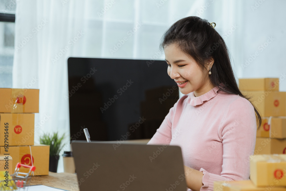 Online store salesperson is writing a customer's shipping address on parcel box before sending it to private carrier for delivery to customer. The idea of opening an online store and packing products. Online store salesperson is writing a customer's shipping address on parcel box before sending it to private carrier for delivery to customer. The idea of opening an online store and packing products.