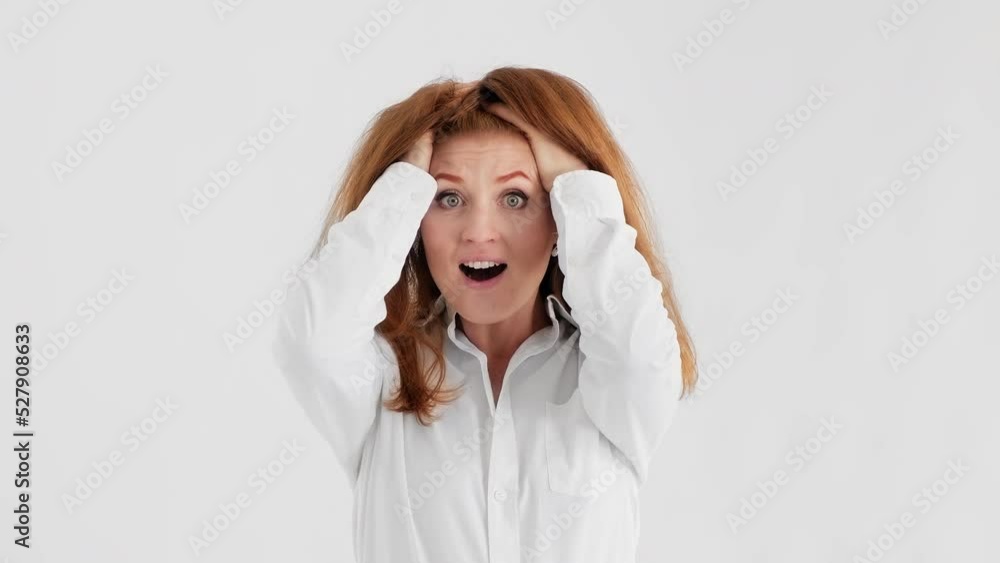 Shocked redhead woman looking at camera with big eyes. Amazed young woman at white background. Surprised female. Wow. 4K, UHD Shocked redhead woman looking at camera with big eyes. Amazed young woman at white background. Surprised female. Wow. 4K, UHD