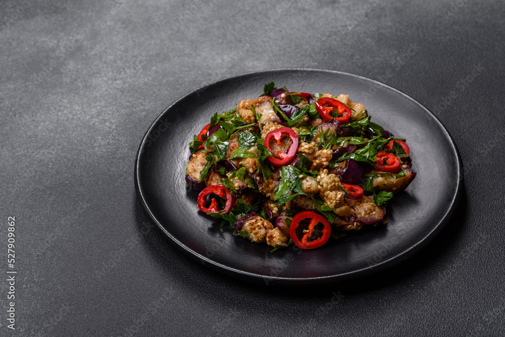 A salad of baked aubergine, sweet pepper, garlic, zucchini and parsley in a black plate A salad of baked aubergine, sweet pepper, garlic, zucchini and parsley in a black plate
