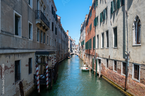 Vue typique d'un canal a Venise avec les reflets, les bateaux et un pont sur fond de ciel bleu © Obatala-photography