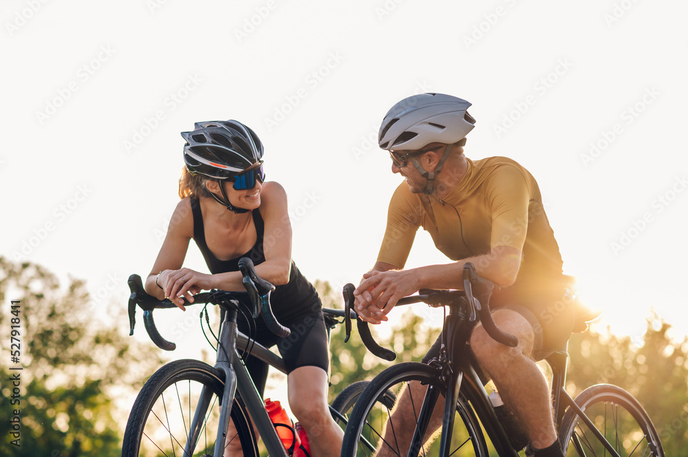 Happy couple riding road bicycles and taking a break during a sunset Happy couple riding road bicycles and taking a break during a sunset