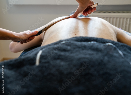 Physiotherapist correcting joint pain of male patient with IASTM tool, Instrument assisted soft tissue mobilization technique for soft tissue treatment.