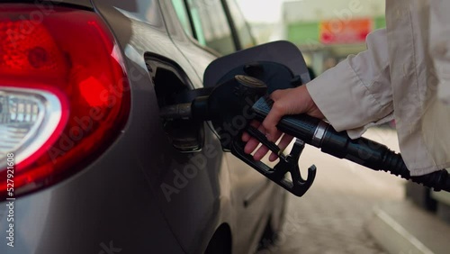 Refueling a car with fuel, Filling fuel into a car tank. Girl driver refuels auto gas station for cars. The car's tank cap is open. Hand holding faucet atomizer for refueling
