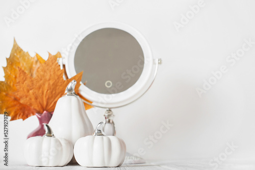 Print op canvas White decorative pumpkins and autumn yellow leaves with mirror on dressing table close-up and copy space