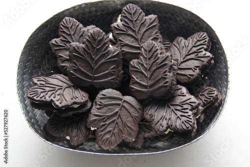 Delicious chocolate cookies filled with vanilla cream made with honey or maple syrup from Canadian trees, the traditional sweet of Canada in gray baket on a white bakground photo