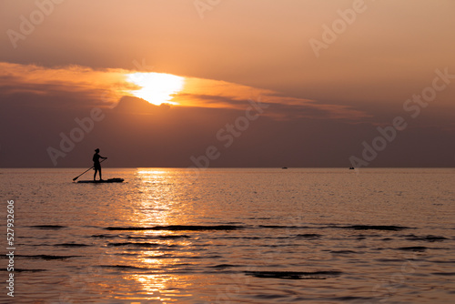 A woman on a sup board with an oar floats on the sea