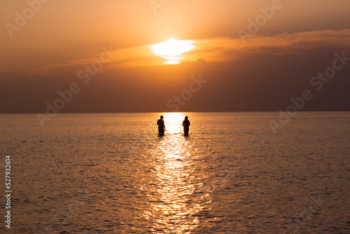 Couple bathing in the sea during a golden sunset