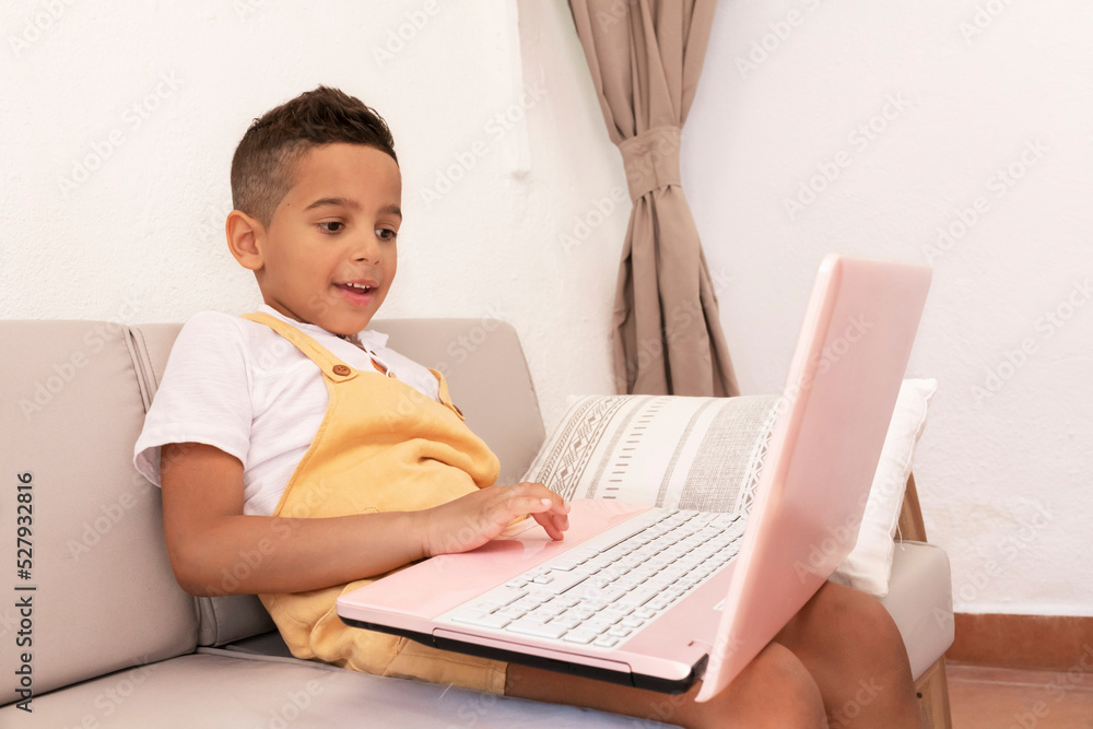 Ethnic boy watching movie on laptop at home Ethnic boy watching movie on laptop at home