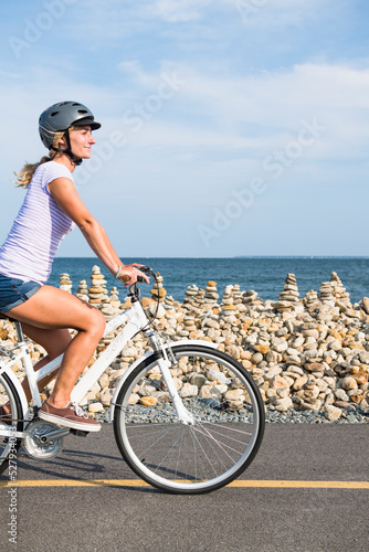 Young Woman biking by Cape Cod beaches coastal bike path