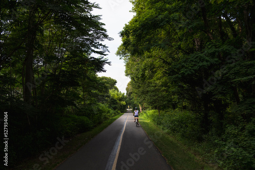 Woman biking through Cape Cod bike path in summer