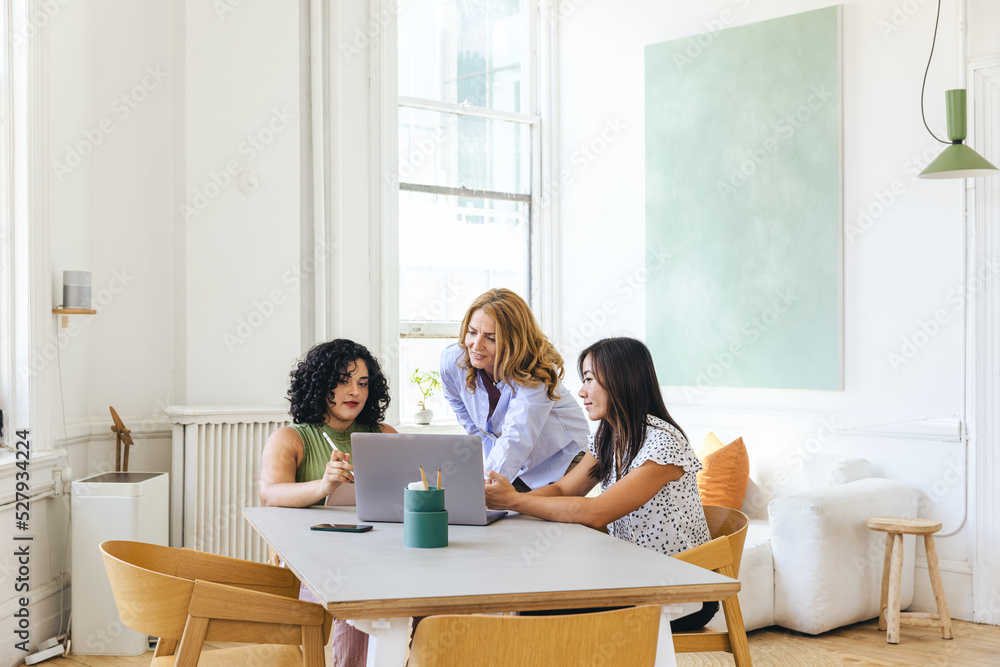 Businesswoman discussing strategy with colleagues over laptop Businesswoman discussing strategy with colleagues over laptop