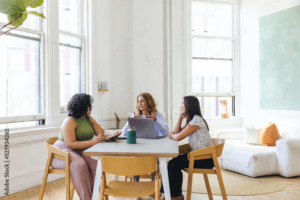 Multiracial businesswomen discussing business strategy at table Multiracial businesswomen discussing business strategy at table