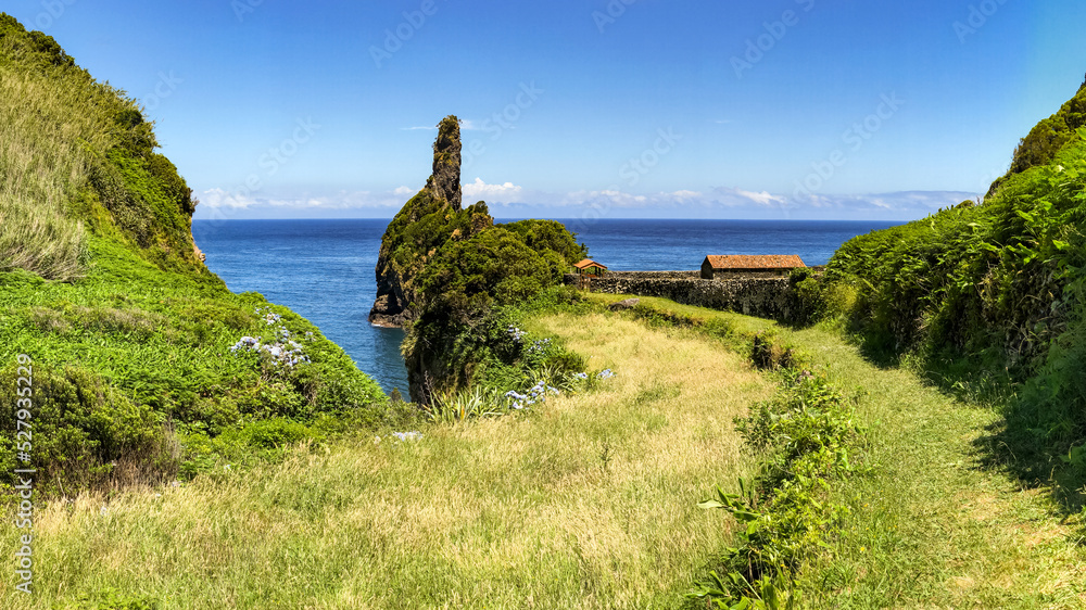 Picturesque panorama with a small picnic area by the sea with rocks and a green meadow Picturesque panorama with a small picnic area by the sea with rocks and a green meadow