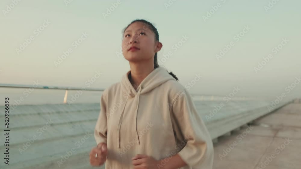 Asian young athletic woman running along the promenade. Sportswoman in sportswear exercising outdoors at morning time Asian young athletic woman running along the promenade. Sportswoman in sportswear exercising outdoors at morning time