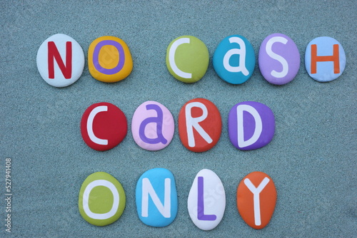 No cash, card only, commercial message composed with multi colored stone letters over green sand