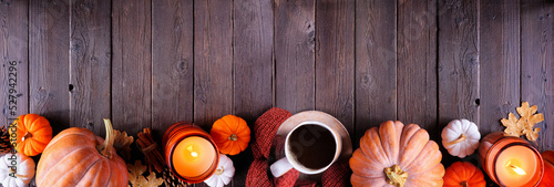 Cozy fall bottom border with pumpkins, sweaters, candles and coffee. Top view over a dark wood banner background. #527942296